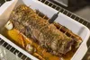 A roast is cooking in a white baking dish with vegetables and a meat thermometer inserted. Voir les images du produit