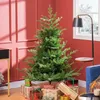 A Christmas tree decorated with gifts in a room with red walls and a window. Podgląd zdjęcia produktu
