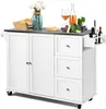 A white kitchen island with a stainless steel countertop is shown against a white background. Various items are placed on the countertop, including bread in a basket, a vase of flowers, a plate of toast, grapes, cheese, and bottles of wine and oil. Náhľad obrázku produktu