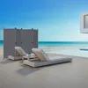 A modern outdoor setting with a beach and ocean view, featuring lounge chairs and a privacy screen. Voir les images du produit