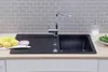 A black kitchen sink with a faucet, lemons, and a soap dispenser on a wooden countertop. Produktbild-Vorschau