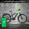 An electric mountain bike is shown against a concrete wall background, with a smartphone displaying a tracking app in the foreground. Produktbild-Vorschau