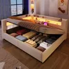 A bed with its storage compartment open, showing neatly folded linens and pillows. Produktbild-Vorschau