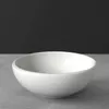 A white bowl on a gray surface with a black background. Náhľad obrázku produktu