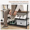 A person is tying their shoe while sitting on a shoe rack with several pairs of shoes on it. Produktbild-Vorschau