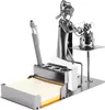 A metal desk organizer with a pen holder, business card holder, and a notepad holder, featuring a metal figurine of a veterinarian examining a dog. Náhľad obrázku produktu