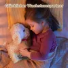 A young girl is lying in bed, hugging a stuffed dog. Produktbild-Vorschau