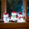 Three illuminated snowman figures are displayed on a windowsill at night, with Christmas lights visible in the background. Produktbild-Vorschau