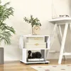 A modern white side table with decorative boxes, a clock, and a camera on it, next to a large potted plant. Podgląd zdjęcia produktu