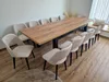 A long wooden dining table with multiple chairs arranged around it in a room. Produktbild-Vorschau