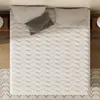 A top-down view of a mattress with pillows on it, placed on a wooden floor next to a rug and nightstands. Voir les images du produit