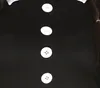 A close-up of a black dress with white buttons and a white collar, with a person's hair visible on the right. Produktbild-Vorschau