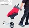 A person is walking while holding a red and black garden shredder on wheels. Voir les images du produit