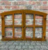 A rusty metal window frame with multiple panes, set against a brick wall and cobblestone ground. Produktbild-Vorschau