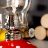 Close-up of a red and white polka dot oil lamp with a glass chimney and a silver wick adjuster. Náhled obrázku produktu