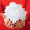 Hands holding a fluffy white material against a red background. Produktbild-Vorschau