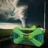 A green emergency radio is placed on a dirt road in front of a dramatic stormy sky with a tornado and lightning. Produktbild-Vorschau