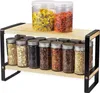 A two-tier wooden shelf with black metal accents, holding various spice jars and two larger clear jars filled with dried herbs and goji berries. Anteprima dell’immagine prodotto