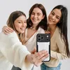 Three young women are taking a selfie together, holding up a phone with a black and white phone case. Produktbild-Vorschau