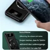 A hand holding a smartphone over a black wireless power bank with a digital display. Produktbild-Vorschau