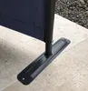 Close-up of the base of a dark blue fabric screen, showing its black metal support pole and a flat metal base plate secured to the ground. Produktbild-Vorschau