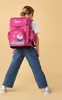 A young girl wearing a backpack, shown from the back. Anteprima dell’immagine prodotto