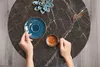 A top-down view of hands holding a cup of coffee on a marble table. Náhled obrázku produktu