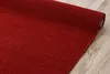 A close-up, angled view of a red carpet rolled up on a wooden floor. Produktbild-Vorschau