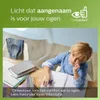 A young boy is sitting at a desk, looking thoughtful while doing homework. The background is a room with a chair and a window. Produktbild-Vorschau