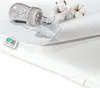 A close-up of a white waterproof mattress protector with a baby bottle and spilled liquid on it, along with cotton balls. Produktbild-Vorschau
