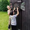 An older man and a boy are playing darts outdoors, with the boy reaching to throw a dart. Náhľad obrázku produktu
