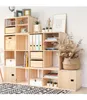 A modular wooden cube shelving unit filled with various items like books, binders, decorative objects, and storage boxes, placed on a patterned rug in front of a white brick wall. Produktbild-Vorschau