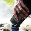 A person's hand holding a black phone case with a stand. Náhľad obrázku produktu