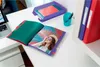 An open folder with a photo of a woman on a beach is displayed on a white desk, next to a laptop and office supplies. Podgląd zdjęcia produktu