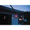 String lights with colored bulbs hanging outside a building at dusk. Produktbild-Vorschau