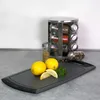 A kitchen counter scene with lemons, herbs, spices, and a cutting board. Anteprima dell’immagine prodotto