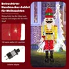 A large illuminated nutcracker soldier decoration for Christmas, displayed outdoors in front of a house with Christmas lights. Produktbild-Vorschau