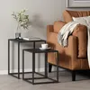 Two nesting tables with a book and a cup of coffee on them, next to a brown sofa with a blanket. Produktbild-Vorschau