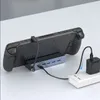 A handheld gaming console is connected to a USB-C hub which is then plugged into a power strip. Produktbild-Vorschau