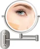 A close-up of a woman's eye and cheek with foundation swatches being tested in a lighted makeup mirror mounted on a wall. Produktbild-Vorschau