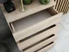 A close-up view of an open wooden dresser with multiple drawers, showing the interior of the drawers. Produktbild-Vorschau