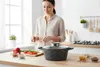 A woman is preparing food in a kitchen, with a pot and ingredients on the counter. Náhľad obrázku produktu