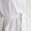 Close-up of a white waffle-weave bathrobe tied with a belt. Náhled obrázku produktu