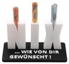 A white 3D-printed object spelling out "NIX" with rolled-up euro banknotes inserted into each letter, placed on a black base with German text. Produktbild-Vorschau
