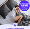 A woman sleeping comfortably in bed with dark gray bedding. Produktbild-Vorschau