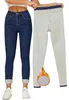 Frau trägt dunkelblaue Skinny-Jeans mit umgeschlagenen Säumen und weißen Sneakers, hält eine hellblaue Jeans mit Flammen-Grafik und warmem Futter hoch Produktbild-Vorschau