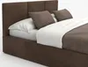 A brown upholstered bed with white bedding and brown pillows, shown from a side angle against a white background. Podgląd zdjęcia produktu
