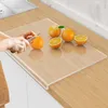 A person is cutting oranges on a transparent acrylic cutting board placed on a wooden countertop. Produktbild-Vorschau