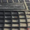 A close-up view of a black rubber car mat with sand and dirt embedded in its textured surface. The mat has a grid pattern and a raised logo or text. Produktbild-Vorschau