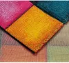 A close-up view of a colorful, patchwork rug with diamond-shaped sections in various bright colors. Produktbild-Vorschau